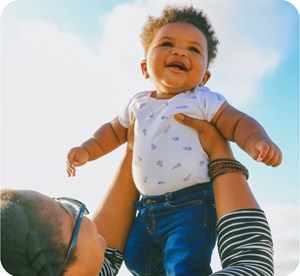 Parent lifting child in air with clear blue sky in background